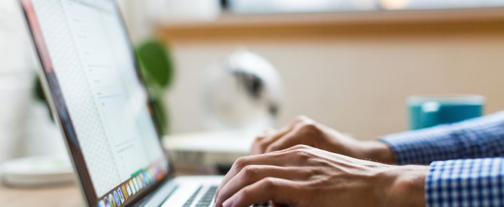 Person typing a guest post on a Macbook laptop